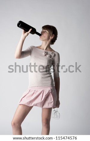 fashion female model holding wineglass and wine bottle posing at light background