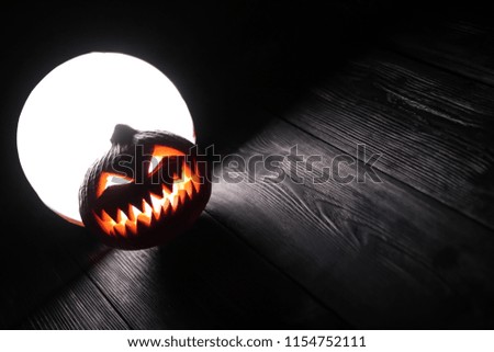 Halloween scary pumpkin Jack-o-lantern on the dark wooden background