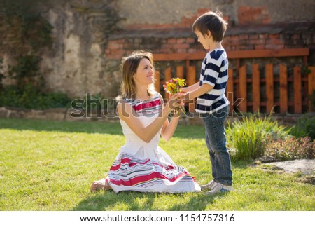 Cute little boy, giving present to his mom for Mothers day in the garden