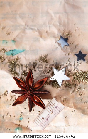 Grungy Christmas background with crumpled old paper scattered with stars , a star anise spice and part of a music score with copyspace