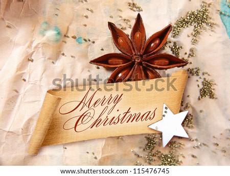 Merry Christmas Greeting on curled banner with star anise spice and a star arranged on crumpled aged paper
