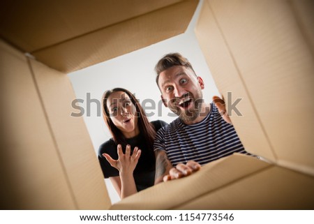 The surprised man and woman opening box and looking inside. The package, delivery, surprise, gift and lifestyle concept