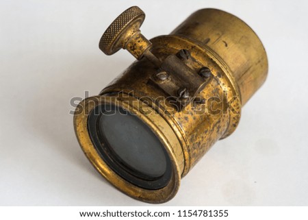 An old camera lens made of copper on a gray background
