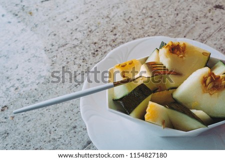 Melon toad skin cut in geometric bowl, on granite countertop, Colorful summer theme