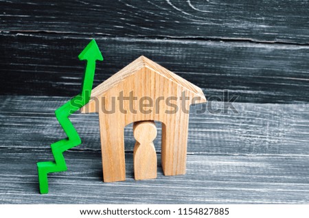 wooden house with a man inside. green arrow up. concept of high demand for real estate. increase energy efficiency of housing. rise in house prices. property. population growth. place for text