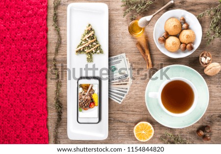 xmas tree wooden table with Christmas new year food, utensils and smartphone with blank screen for app over cooking book on. Top view. Recipe and menu background. flat lay. Mock up. Free copy space.