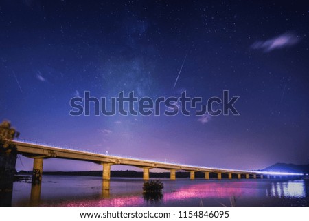 Night image of a bridge over the water with rain of stars