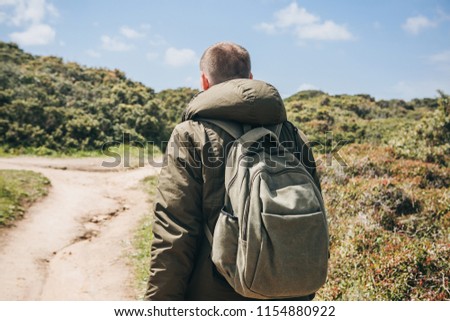 A tourist with a backpack or traveler walks through the hilly terrain.