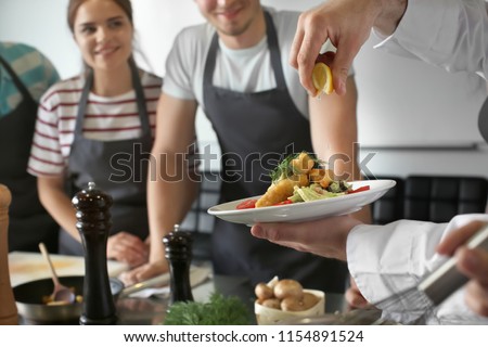 Male chef holding plate with prepared dish during cooking classes Royalty-Free Stock Photo #1154891524