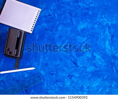 desktop in the office or student. Notepad, pen on a blue background.