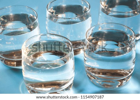 Glasses of water on pastel blue. Water balance for healthy. Pattern. Close up.