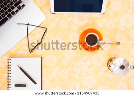 Flat lay photography. Top view table desk. Laptop, glasses, tablet, espresso cup, coffee maker, croissant, notebook and pen with blank space on a towel background. Morning concept.