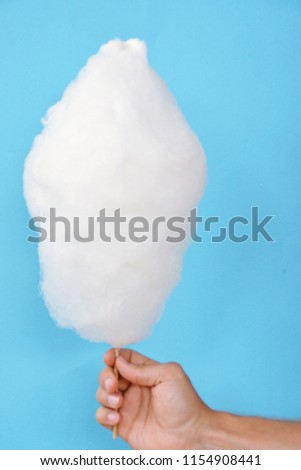 Close-up - man holds cotton candy from a german kermis in front of a monochrome background in hand