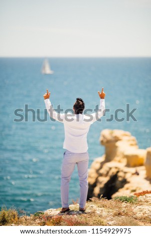 Rear view of Young handsome man pointed up on ocean background