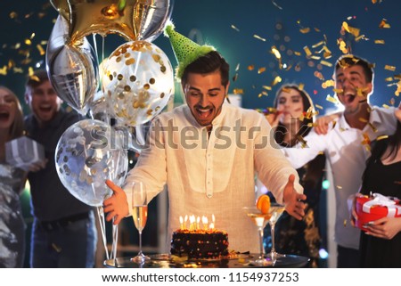 Young man near his birthday cake at party in club