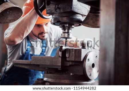 Experienced operator in a hard hat. Metalworking industry concept professional engineer metalworker operating CNC milling machine center in manufacturing workshop. Royalty-Free Stock Photo #1154944282