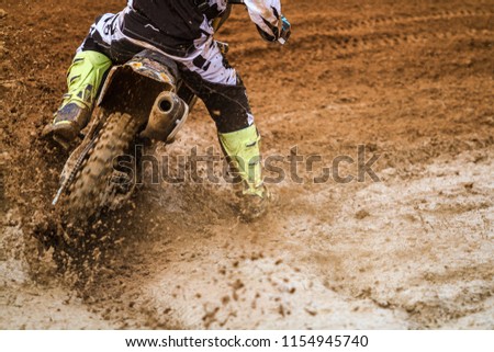 Close up of motocross racer accelerating in dirt track