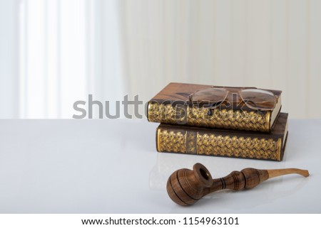 Two old books with a pair of glasses on them and a tobacco pipe in front of bright background. The teachers day. Back to school. Space.