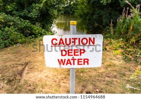 Caution deep water sign, by the side of a large lake, river, hazard, danger