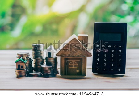 House placed on coins and calculator is on the wood. planning savings money of coins to buy a home concept concept for property ladder, mortgage and real estate investment. for saving for a house.
