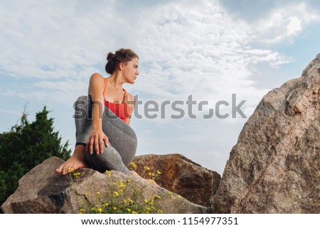 Grey leggings. Appealing athletic woman wearing grey leggings and red top working on her flexibility
