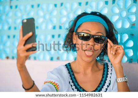 young happy and attractive Southeast Asian Indonesian woman taking selfie photo portrait with mobile phone camera posing cheerful and playful at beautiful background in holidays travel 