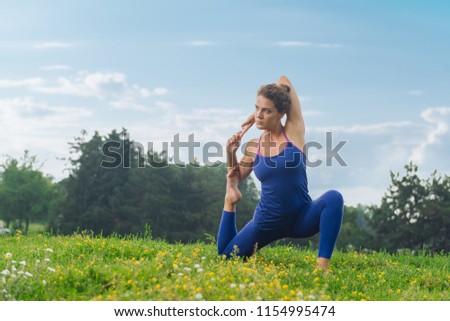 Stretching time. Slim beautiful woman feeling rested and contended while stretching sitting on green grass