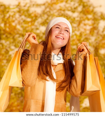 Picture of cute cheerful girl with shopping bags, attractive stylish woman rejoice her presents bags, pretty female in autumn park enjoying spending money, autumnal sales concept