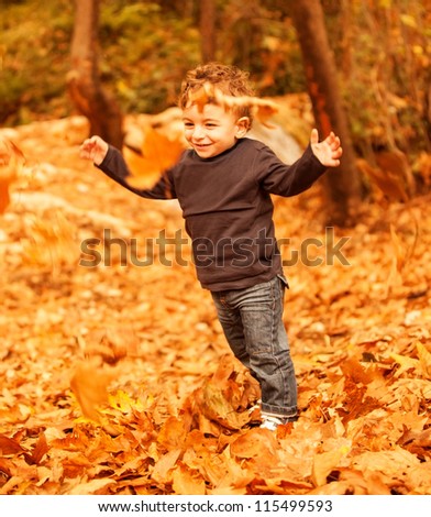 Picture of cute little boy run with raised up hands in autumnal woods, pretty small male walking in the park, cheerful infant having fun in fall forest, adorable toddler play game on backyard