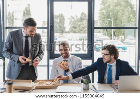 happy young office workers eating pizza at workplace  