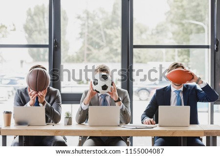 young office workers holding balls while working with laptops in office   Royalty-Free Stock Photo #1155004087