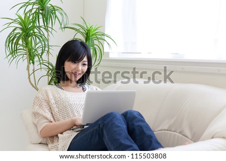 a young asian woman using laptop on the sofa