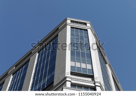 Corner of modern business centre, architecture details. Metallic grey facade of skyscraper. Bottom view of modern building in business district against blue heavens
