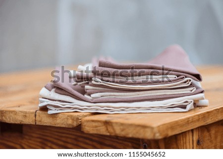 A stack of linen textiles on a wooden table
