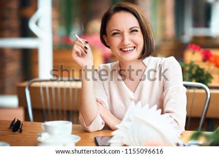 Young woman smokes tobacco in a cafe
