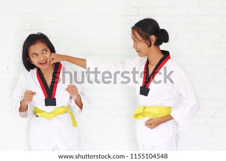 Portrait young cute girls play taekwondo together with white background.