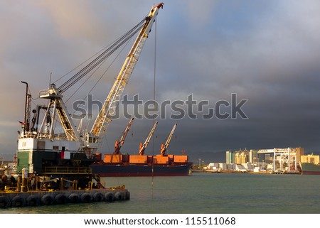 Dredger digging a shipping channel in the Port of Oakland, California.  The city's downtown buildings can be seen in the background.