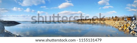 Beautiful colorful view of the Partwitzer lake beach in Germany, floaded sand quarry, blue azure water with mirror water surface, the bright blue sky with clouds is reflected in the watery surface