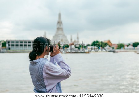 Asian woman solo travelers and take photo ancient pagoda buildings- Temple of Dawn temple or Wat Arun- Bangkok -Thailand- Asia.