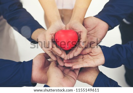 The rubber red heart on hands holding of a diverse and support team of men and women with business health, coworker are unity, love care, sacrifice, charity, cooperation in teamwork build a network 