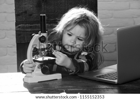 student boy with laptop and microscope study science at educational workplace makes experiment