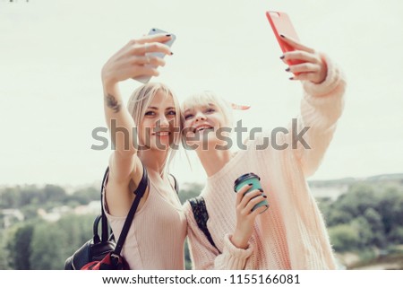 young pretty woman posing in the street with phone, outdoor portrait, hipster girls, sisters, chic, tablet, internet, using smartphone, close-up fashion model, post in instagram, facebook, make selfie