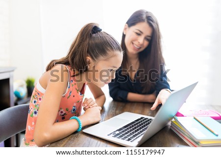 Girl and teacher using laptop during homeschooling at table Royalty-Free Stock Photo #1155179947