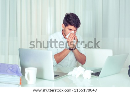 Sick man with handkerchief sneezing blowing nose while working in office, businessman caught cold, seasonal flu. Pandemic influenza, disease prevention, air conditioning in office cause sickness Royalty-Free Stock Photo #1155198049