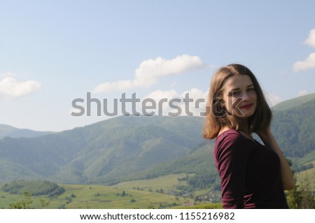 Woman sits with her back in the field and admires the sunset in the mountains. Happy woman on the sunset in nature in summer