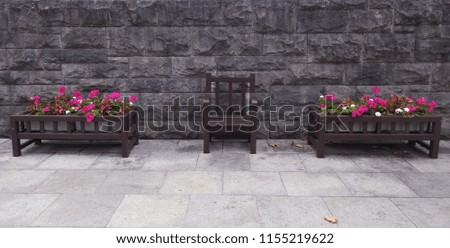 wooden flower containers and seat against a brick wall background