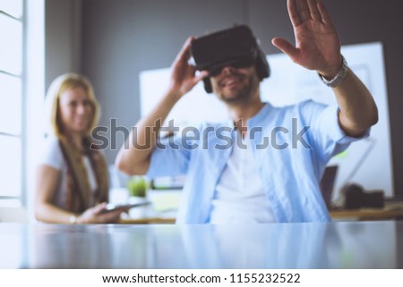 Young male software programmer testing a new app with 3d virtual reality glasses in office.