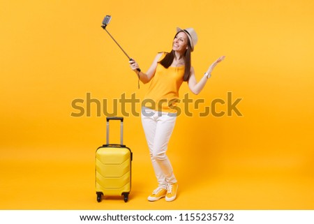 Happy tourist woman in summer casual clothes, hat doing selfie shot on mobile phone isolated on yellow orange background. Passenger traveling abroad to travel on weekends getaway. Air flight concept