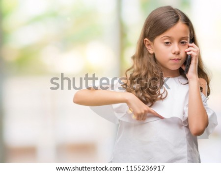 Brunette hispanic girl using smartphone with surprise face pointing finger to himself