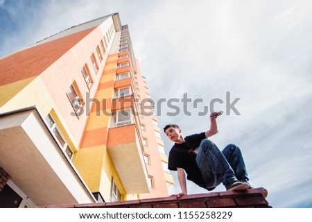 Teenage boy on a street in a big city next to a high-rise building alone. concept of a teenager parkour life. height portrait on a high-rise building background close